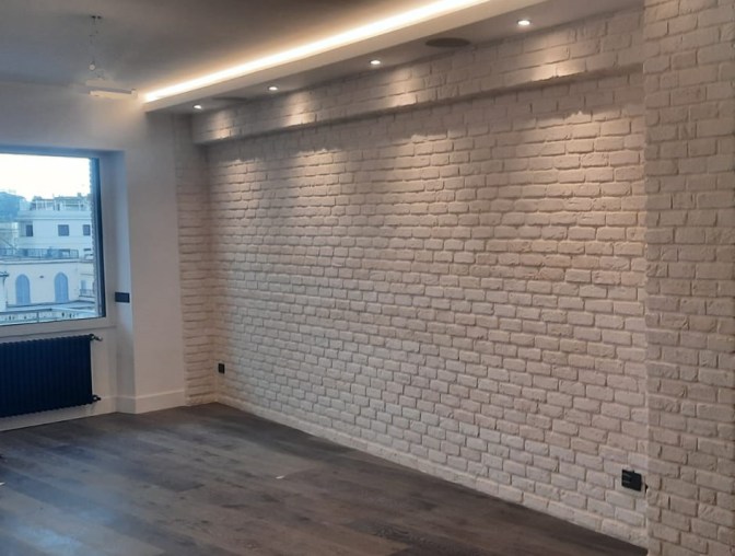 Una parete di un living rivestita in mattone bianco
